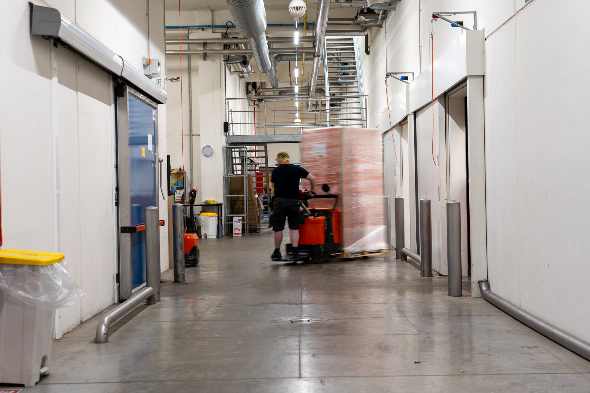 magazijnier brengt pallet van productieruimte naar de magazijnen via de middengang